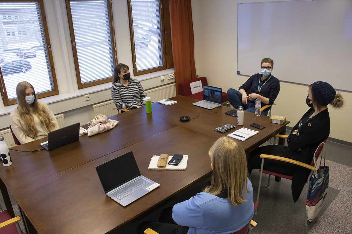 tiimi kokoontuneena pöydän ääreen suunnittelemaan