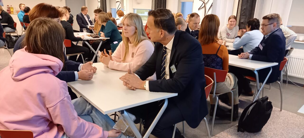 Nuoret keskustelee aikuisten päättäjien kanssa pöydän ääressä